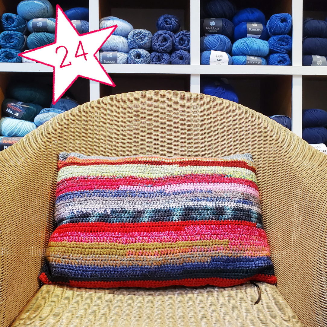 Buntes Häkelkissen auf Rattansessel